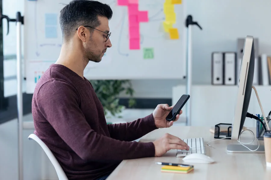 Palabras clave en wordpress optimización de palabras - Profesional usando un smartphone frente a su escritorio