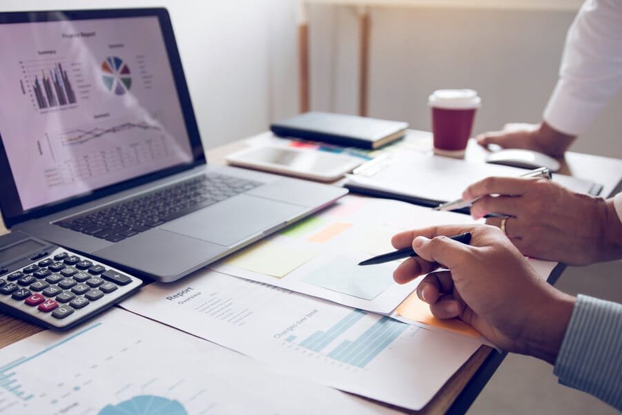 Que es tráfico orgánico en marketing importancia del tráfico - Manos revisando gráficos y análisis financieros en una oficina con laptop y documentos
